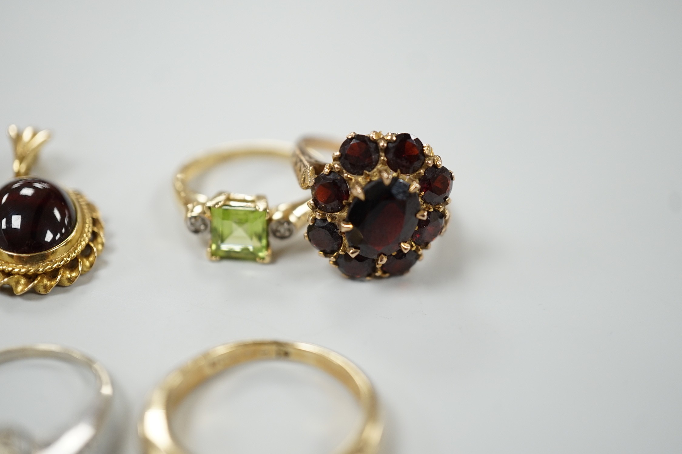 A 9ct and garner cluster set dress ring, size M, gross 4.9 grams, two yellow or white metal and diamond set rings, including half eternity and a yellow metal and garnet set half hoop ring, gross 8.8 grams, a 14k, single